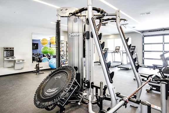 A gym with a variety of equipment including a treadmill, a weight bench and a rowing machine.
