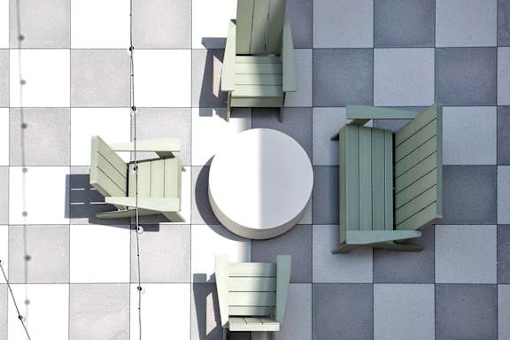 A white table is surrounded by four green chairs.