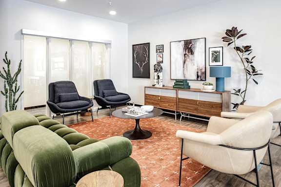 A living room with a green sofa, two black chairs, and a white chair.