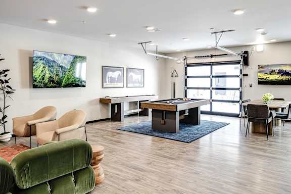 A room with a table, chairs, and a TV on the wall.