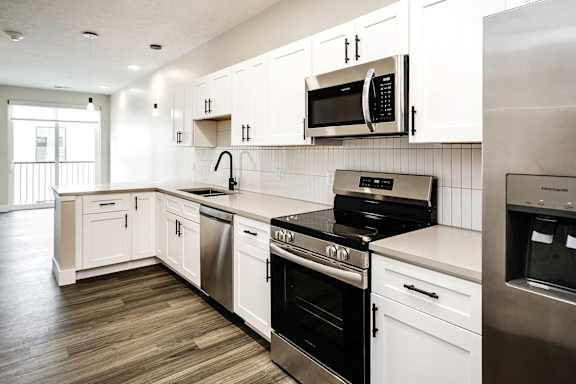 A modern kitchen with white cabinets and stainless steel appliances.