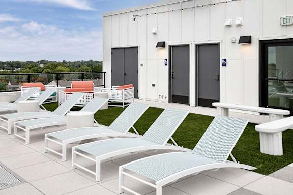 A row of white and blue sun loungers are on a patio.