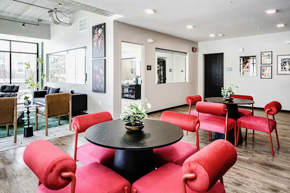 A black table surrounded by red chairs in a room.