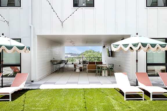 A white patio with a table and chairs under umbrellas.
