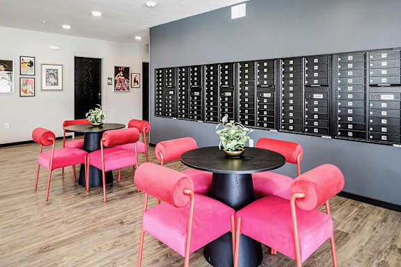 A room with a table surrounded by red chairs.