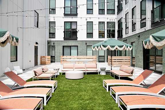 A patio with a white table and chairs with orange cushions.