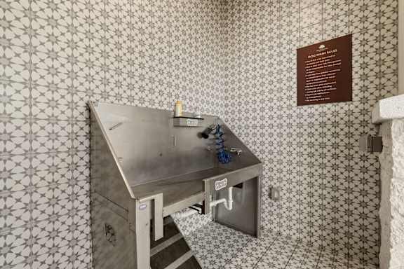 A metal box with a blue handle is on a tiled floor.