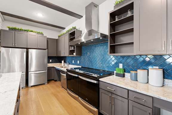 A kitchen with a blue backsplash and wooden floors.