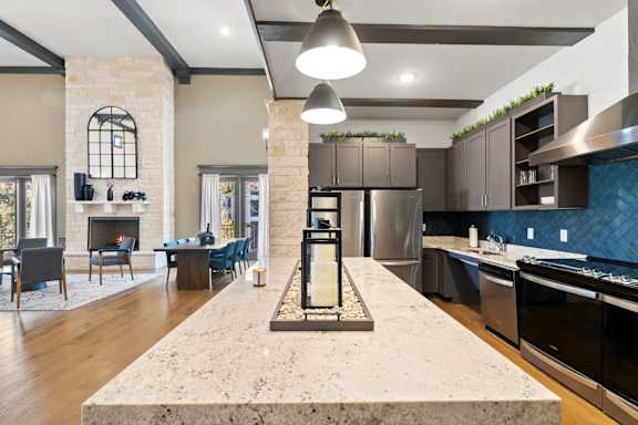 A modern kitchen with a stone fireplace and a marble island.