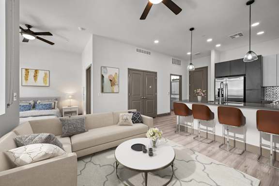 A modern living room with a beige sofa, a coffee table, and a bar area with stools.