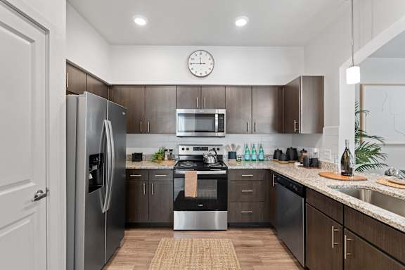 A modern kitchen with a refrigerator, oven, and microwave.