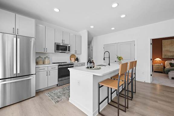 A modern kitchen with a white island and stainless steel appliances.