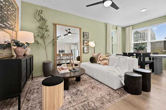 A living room with a white couch, a black dresser, a round table, and a large window.