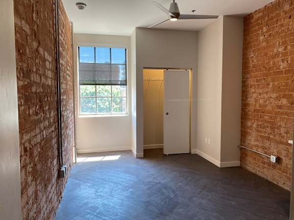 A room with a brick wall and a ceiling fan.