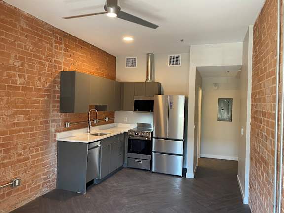 A kitchen with a brick wall and stainless steel appliances.