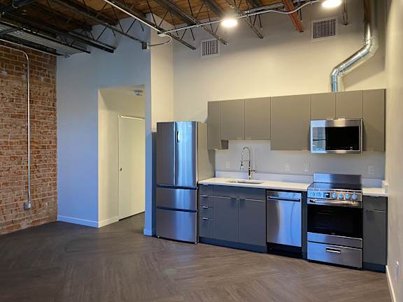 A kitchen with a refrigerator, sink, and oven.