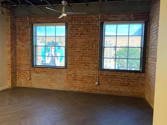 A room with a brick wall and two windows.