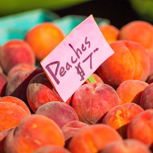 a pile of peaches with a sign on top of them
