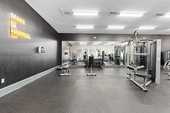 A gym with a neon sign that says "make it happen".
