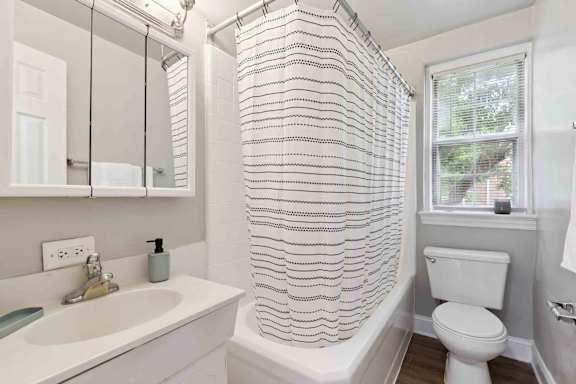 A white bathroom with a striped shower curtain.
