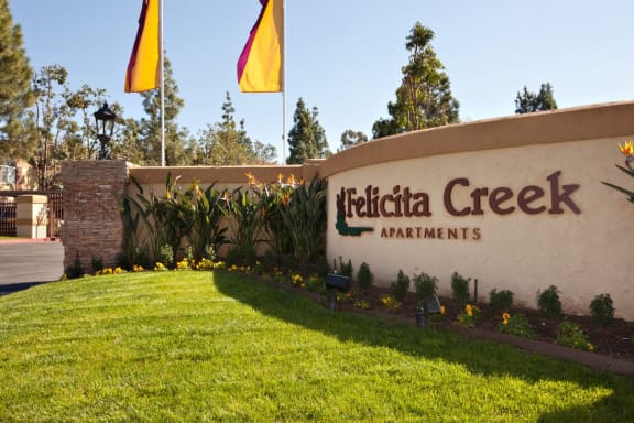 a building with a sign that says hetica creek apartments with flags flying in the background