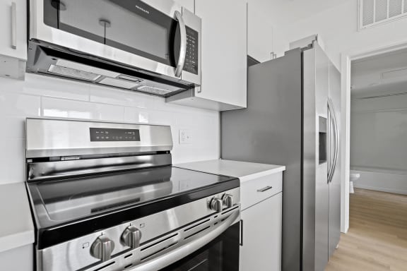 a kitchen with white cabinets and stainless steel appliances and a refrigerator