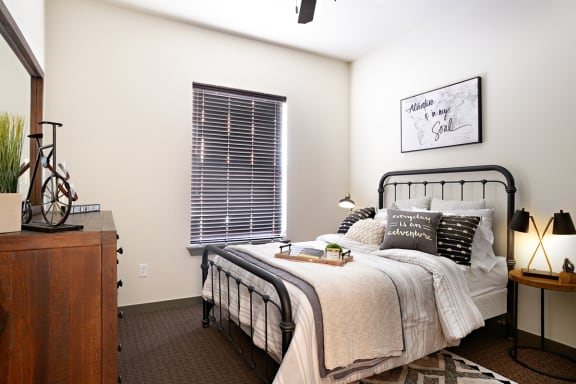 a bedroom with a bed and a dresser and a window at The Liberty Lofts, Gainesville, TX, 76240