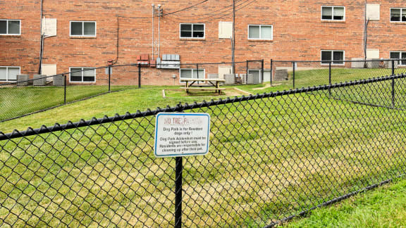 Sign on a chain link fence in front of a brick building
