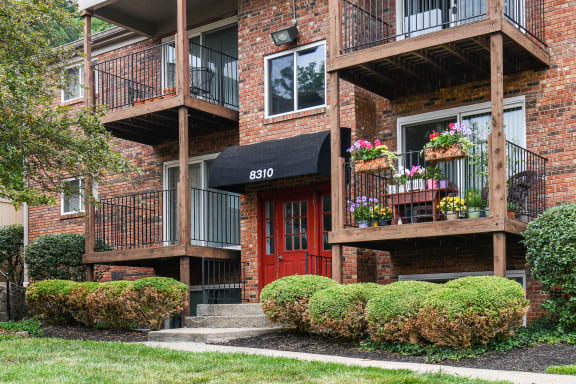 Front of a brick apartment building with a red door and balconies
