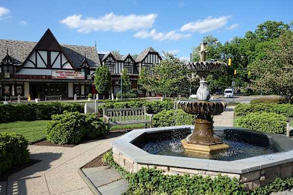 A fountain in the middle of a park with a building in the background.