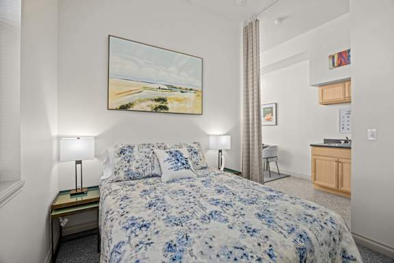 A bedroom with a large bed and a painting on the wall.