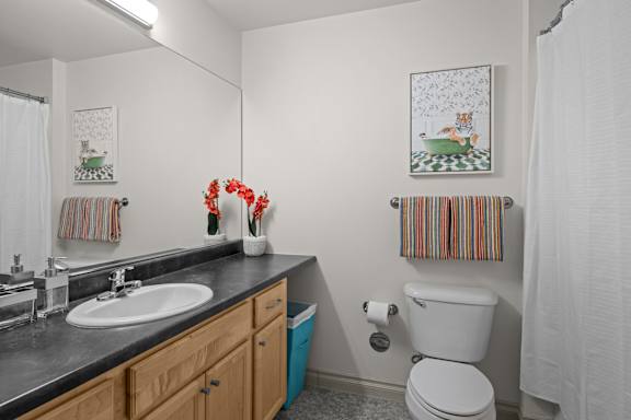 A bathroom with a toilet, sink, and towels.