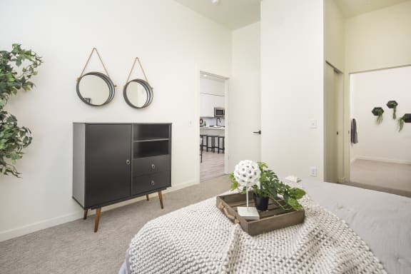 a bedroom with a bed and a dresser and two mirrors on the wall