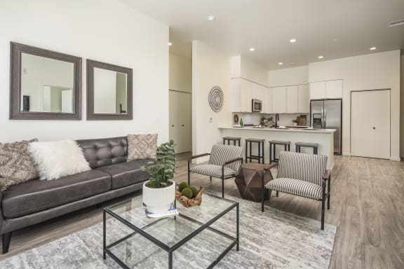 a living room with a couch and chairs and a glass table