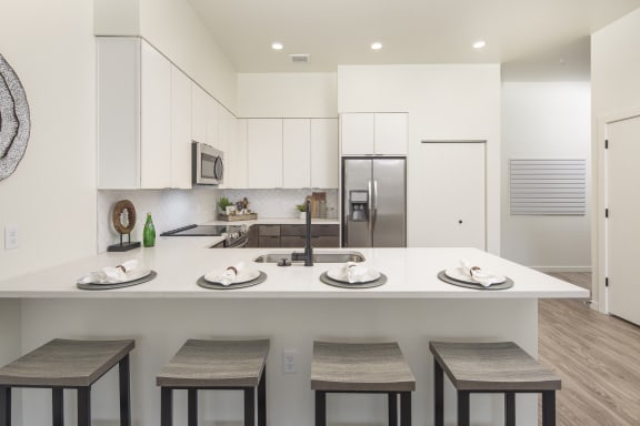 an open kitchen with a large island with plates and chairs