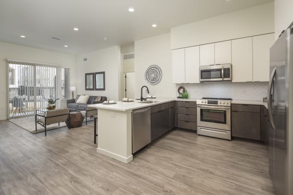 a kitchen and living room with white cabinets and stainless steel appliances