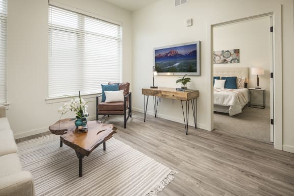 a living room with a couch and a table and a bedroom in the background