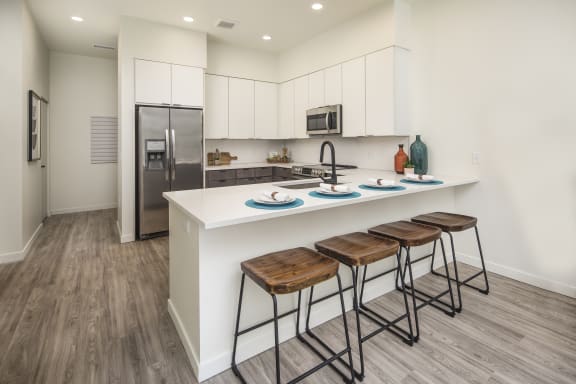 a kitchen with white cabinets and a counter with three stools