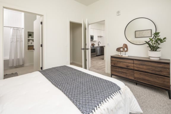 a bedroom with a bed and a dresser and a bathroom