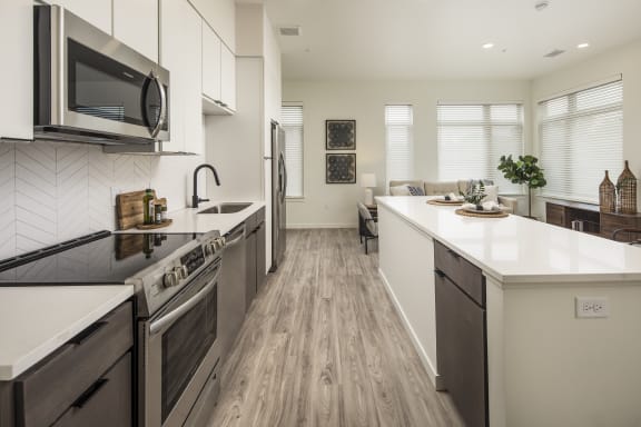 an open kitchen and living room with a large island and a stove and a microwave