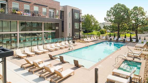 a swimming pool with lounge chairs and a building in the background at Cycle Apartments, Fort Collins
