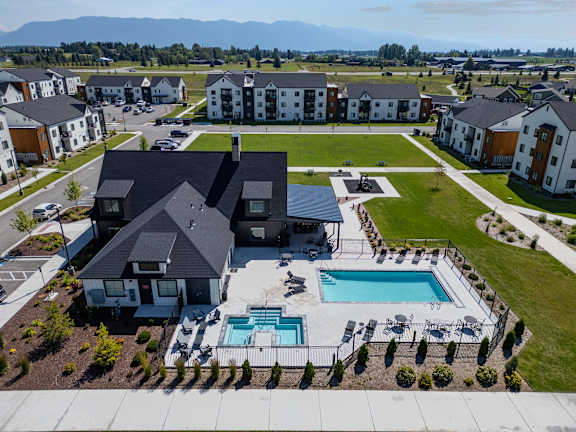 A large house with a pool in the foreground and several smaller houses in the background.