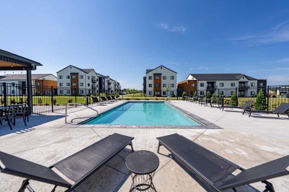 A swimming pool surrounded by lounge chairs and buildings in the background. at Silverbrook Apartments, Montana, 59901