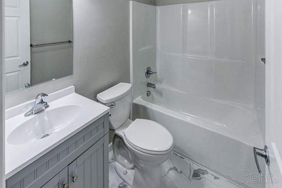 A white toilet sits next to a white sink in a bathroom.