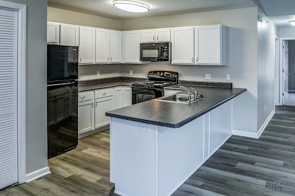 A kitchen with white cabinets and a black countertop.
