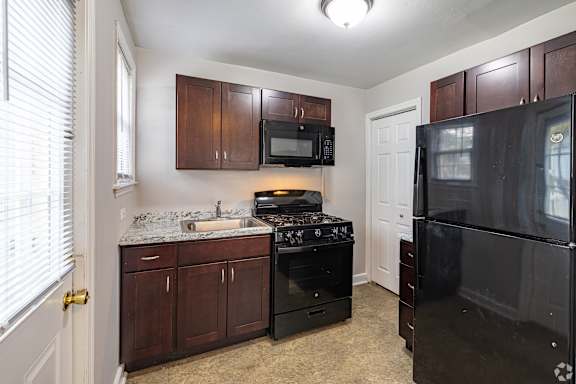 A kitchen with a black refrigerator and black stove.