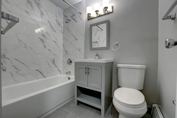 A bathroom with a marble wall and a white toilet.