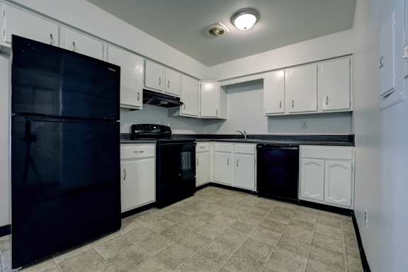 A kitchen with black appliances and white cabinets.