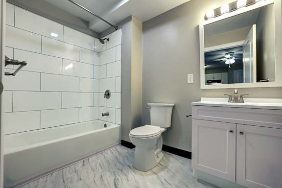 A white toilet sits in a bathroom next to a sink and a mirror.