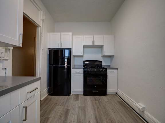 A kitchen with black appliances and white cabinets.